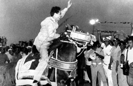 Gaddafi waves to a crowd as he rides a horse during a ceremony marking the sixth anniversary of the eviction of Italians from Libya. 1976(AP)